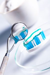 A dental mirror next to a toothbrush with toothpaste