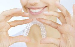 A close-up of a clear mouth guard being held by a woman