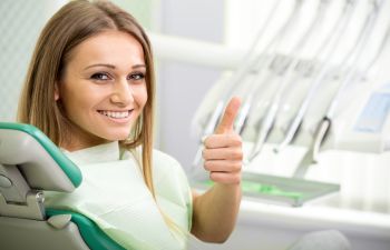 girl shows thumbs up on the dental chair