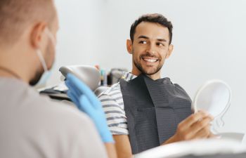 A dentist and a happy man with a perfect smile after a smile makoever treatment.