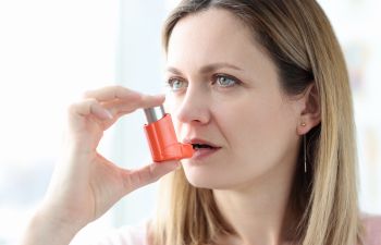 A woman using an inhaler.