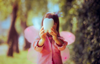 little girl in tooth fairy costume holding a molar toy